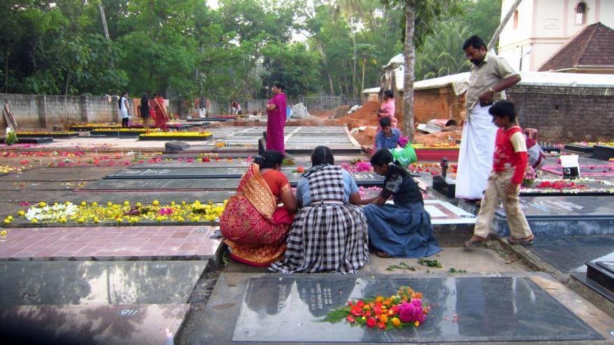 Tombstones are decorated with fresh flowers at St. Mary's Forane Church in the early morning before the start of the Syro-Malabar Day of the Dead procession in India. Women decorate tombstones before the Day of the Dead procession in India.