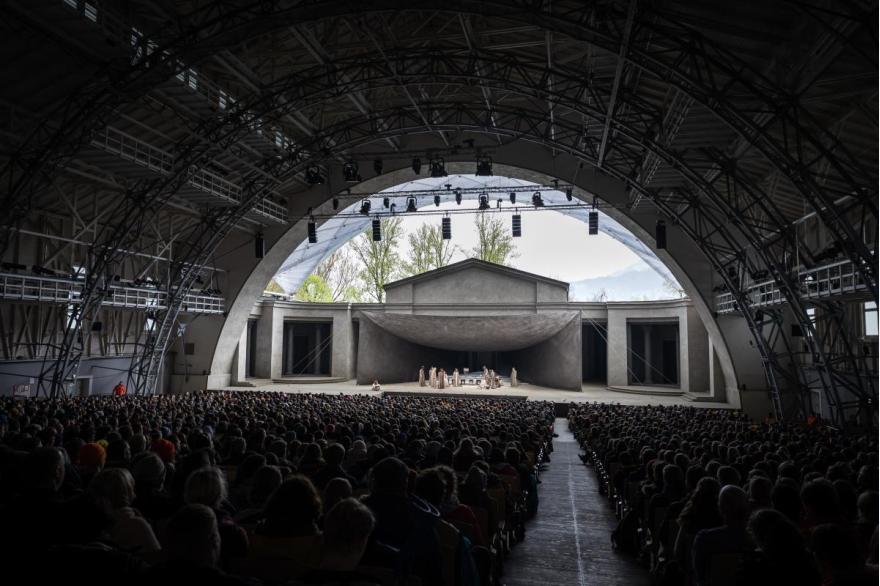 A near capacity crowd fills the seats of the Passion Play Theater under an arched roof.