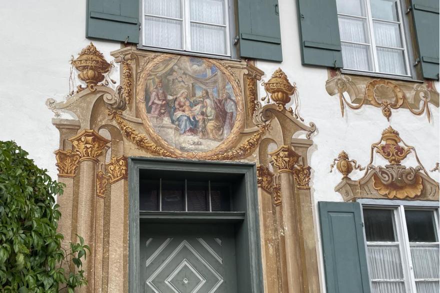 The stucco exterior of a building painted with elaborate decorative columns and religious scenes.
