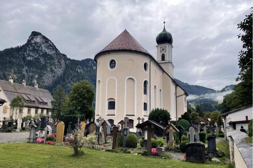 A small cemetery behind the baroque church with a view of the alps behind.