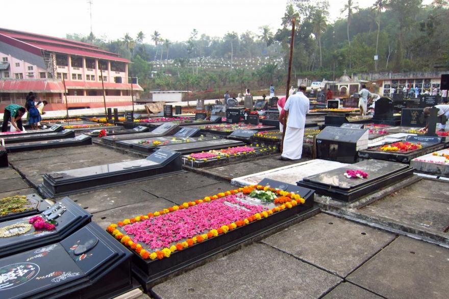 Decorating tombstones with fresh flowers at St. Mary's Forane Church in the early morning before the start of the Syro-Malabar Day of the Dead procession.