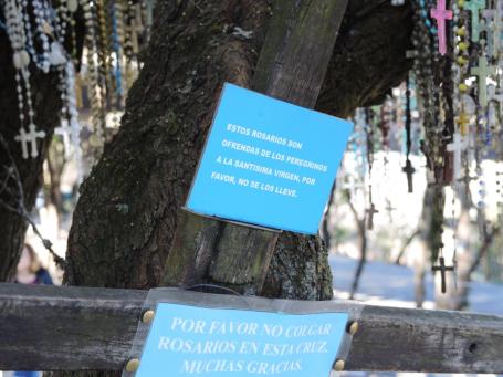 A sign tells visitors that the rosaries strung on tree branches are the offerings of pilgrims to the Virgin, and please don't take them. Another asks pilgrims not to hang their rosaries on the cross.