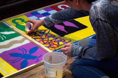 Art students at the College of the Holy Cross create designs from colored sand, interpreting the street carpets created in many Latin American countries for Holy Week processions.