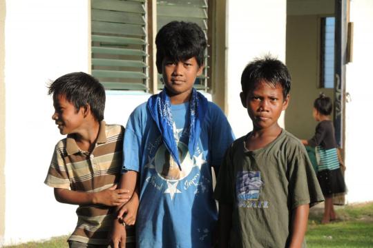 Boys await the start of the Advent Penance Service outside the church in Fono, Chuuk. The happy 1st birthday shirt refers to a major, important event in Chuukese culture.